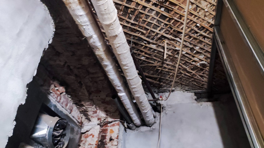 Изоляция труб и кирпичная стена под потолком старого здания