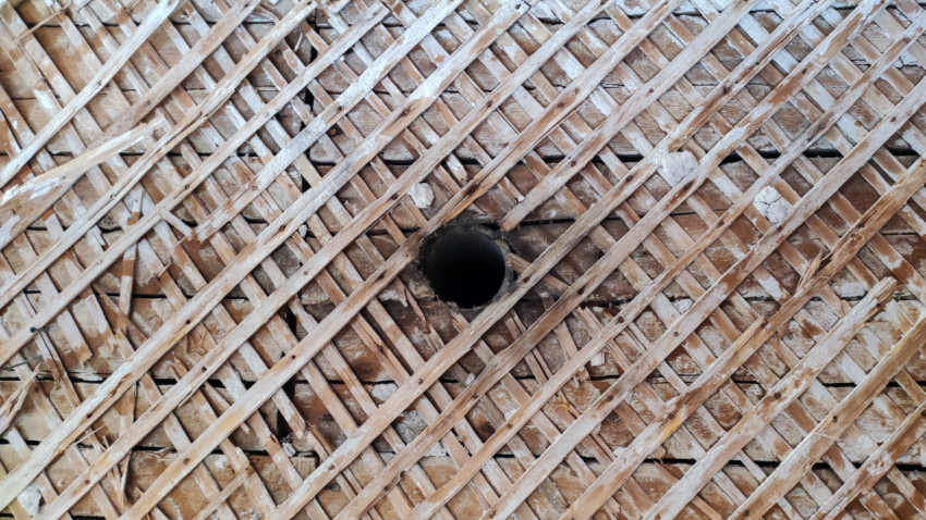 Деревянная дранка с круглым отверстием в стене старого здания