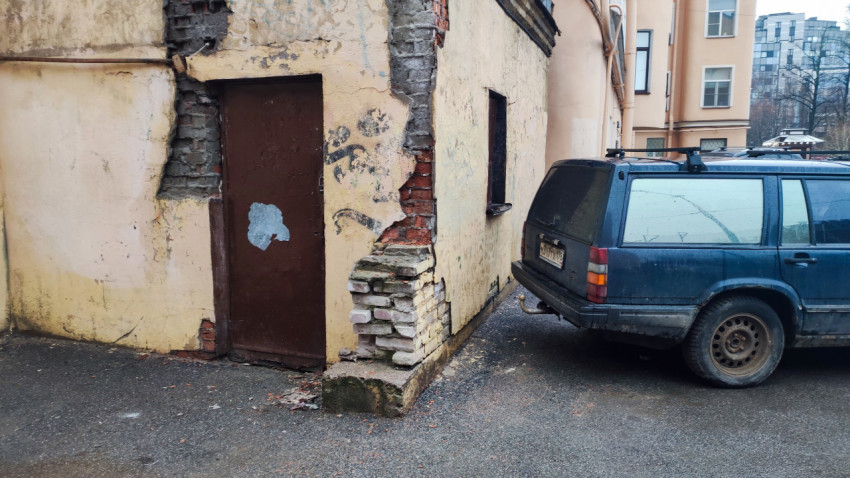 Разрушающийся угол хозяйственного здания во дворе