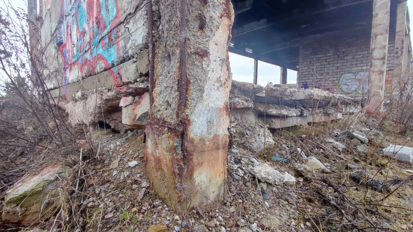 Ржавеющая бетонная колонна и осыпающийся фундамент здания