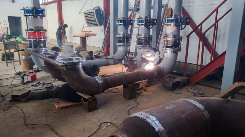 Рабочие сваривают крупные трубы на производстве