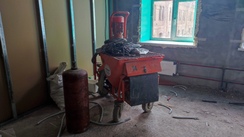 Штукатурная станция и газовый баллон на стройплощадке помещения
