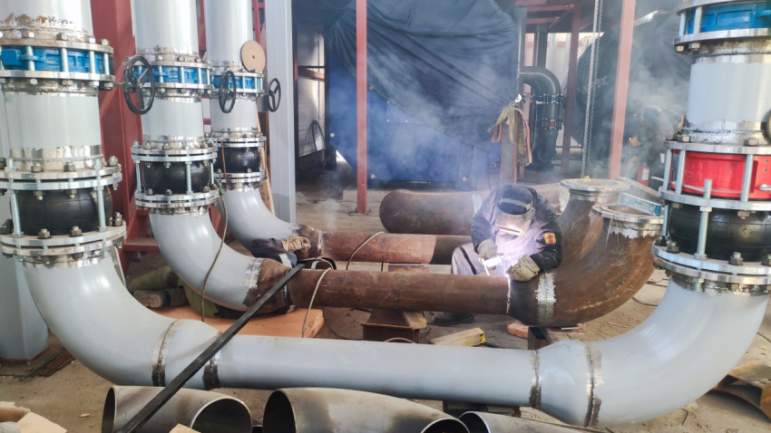 Сварщик соединяет стальные трубопроводы в промышленном цехе