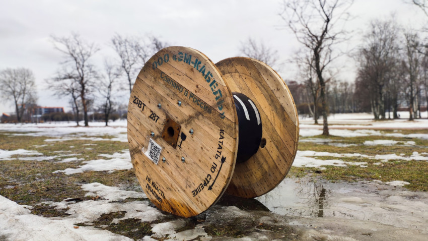 Деревянный барабан с кабелем на фоне парка в снегу