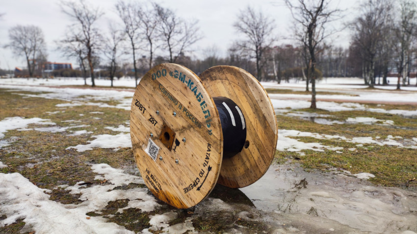 Деревянный барабан с кабелем на фоне парка