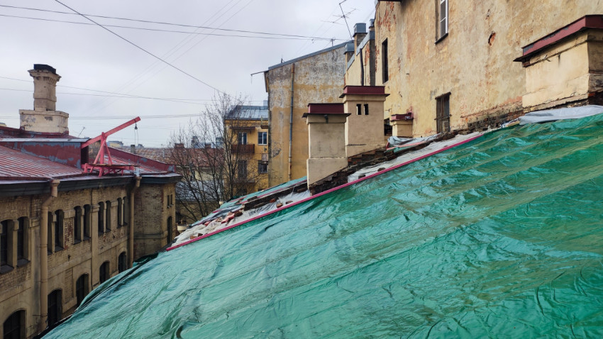 Крыша старого дома с зелёным укрытием во время ремонта