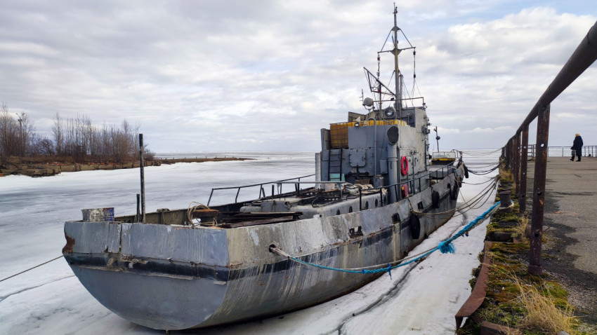 Старое техническое судно на льду у северного причала