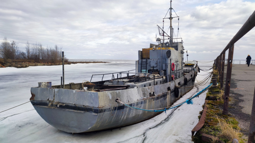 Старое судно у замерзшего причала в зимнем порту