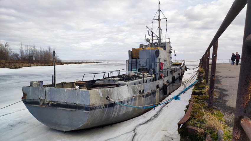Металлическое судно у бетонного причала в ледяной гавани