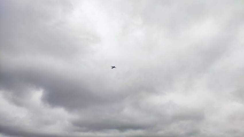 Самолёт в облачном небе над горизонтом