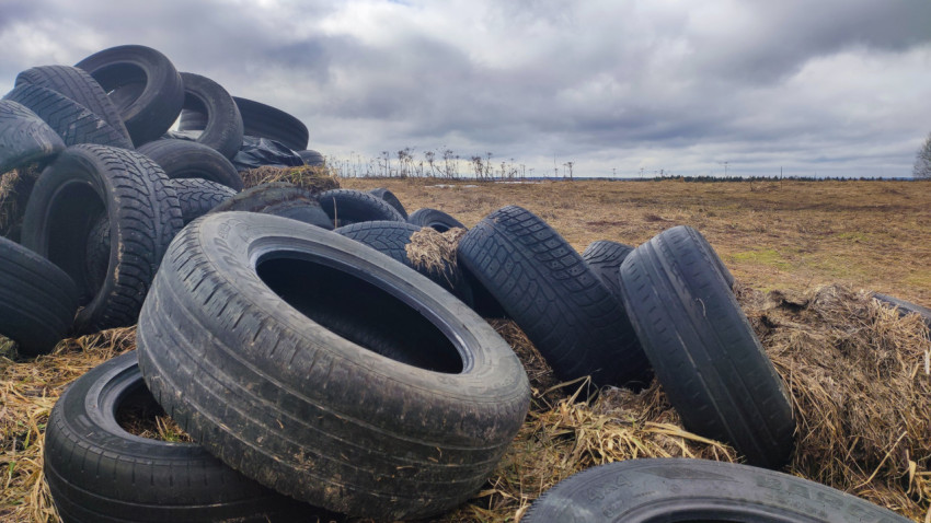 Крупный план старых шин с остатками травы на фоне поля