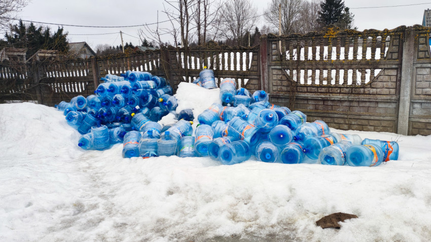 Скопление пустых бутылей для воды на заснеженной площадке