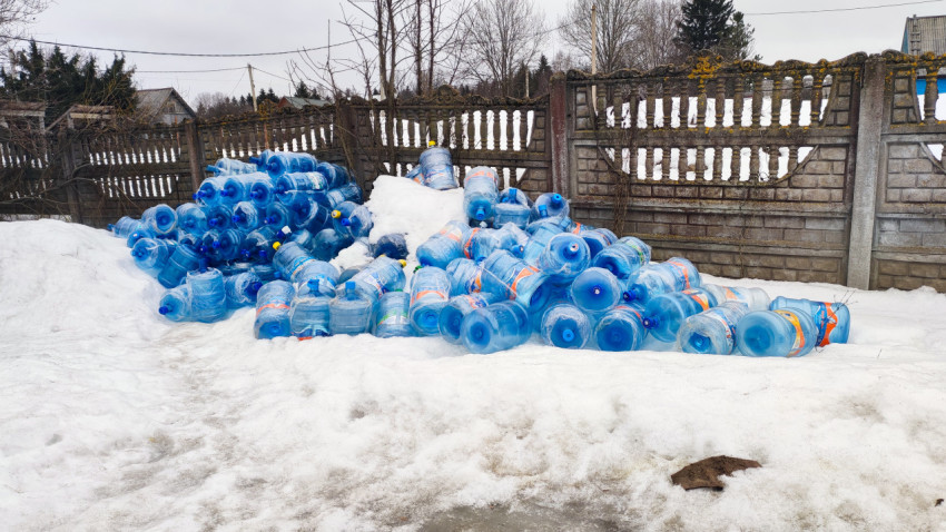 Пластиковые бутылки на снегу у бетонного забора