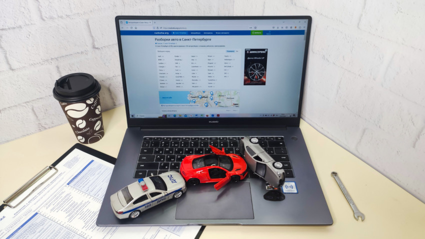 Рабочее место страхового эксперта с ноутбуком и моделями машин