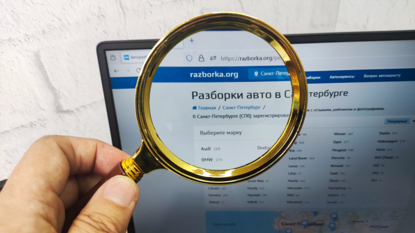 Лупа над экраном ноутбука с сайтом автомобильной разборки