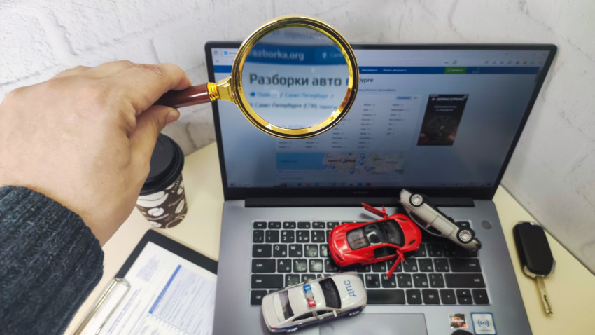 Лупа и ноутбук с моделями автомобилей при анализе авторазборки