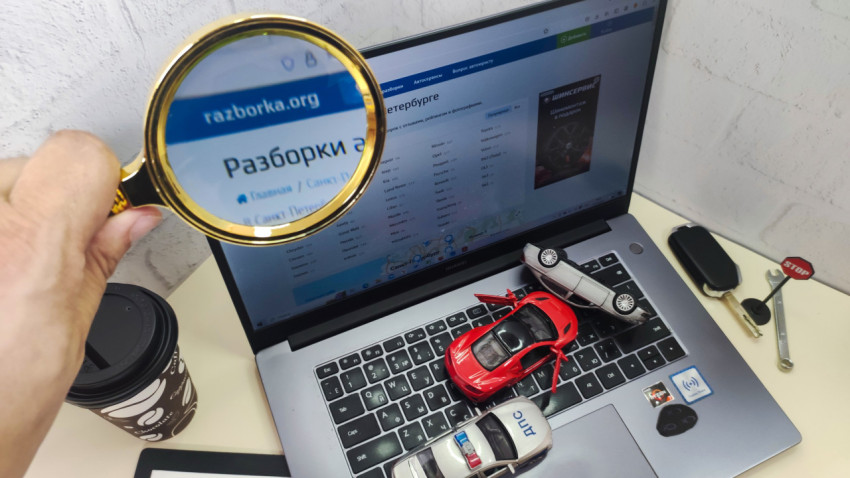 Лупа с фокусом на сайт razborka.org и модели машин на ноутбуке