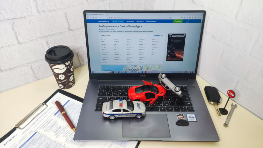 Рабочее место с ноутбуком и моделями автомобилей на клавиатуре