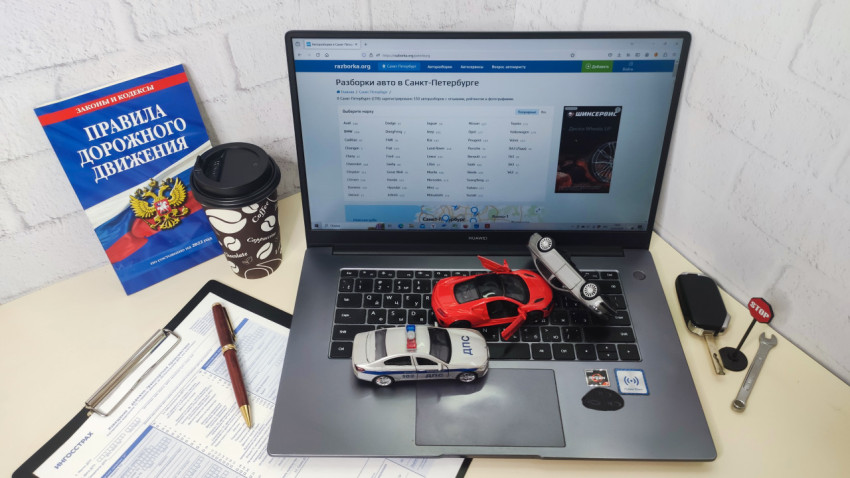 Рабочее место с ноутбуком, моделями автомобилей и ПДД
