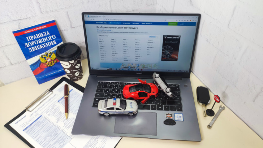 Рабочий стол с ноутбуком, модельными автомобилями и справочником ПДД