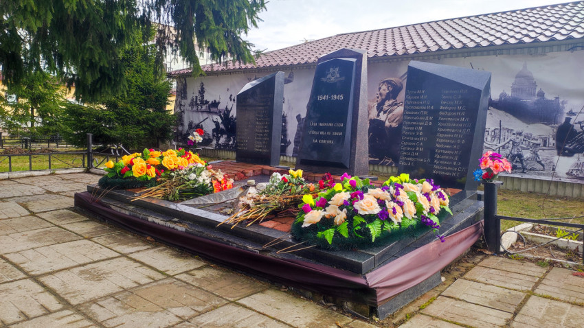 Мемориальный комплекс с именами погибших и цветочными композициями