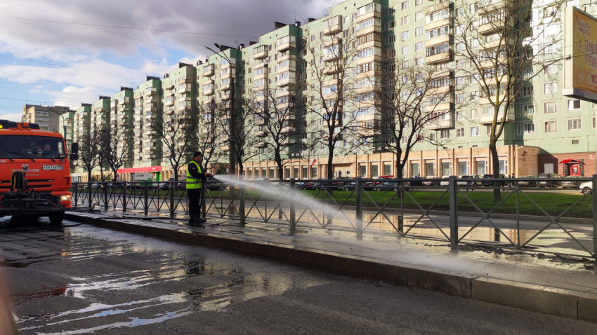 Специалист коммунальных служб моет ограждение на разделительной полосе