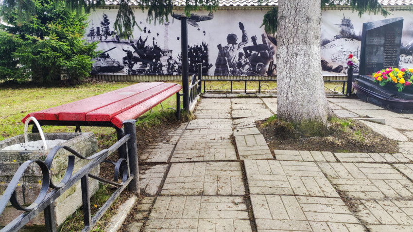 Зона мемориала с плиточным покрытием и стендом с историческим панно