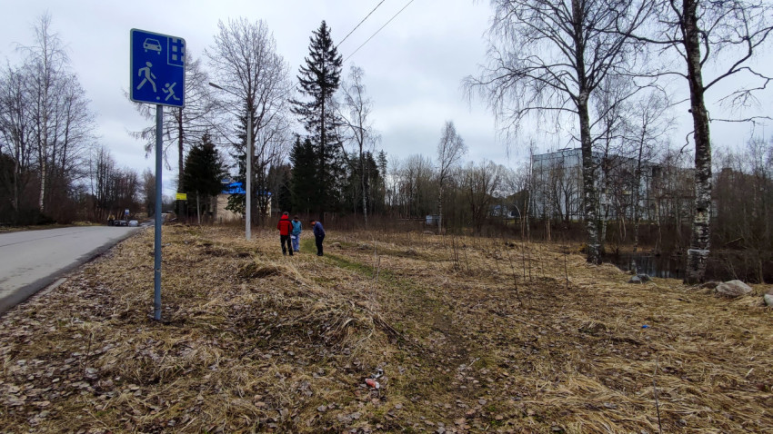 Люди на пригородной поляне рядом с дорожным знаком