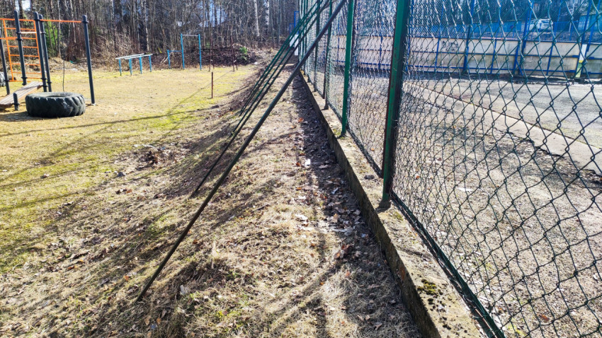 Опорные стойки ограждения рядом с уличным тренажёром