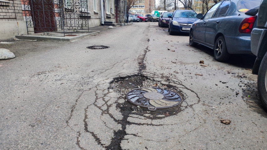 Разрушенное дорожное покрытие вокруг люка на дворовой улице