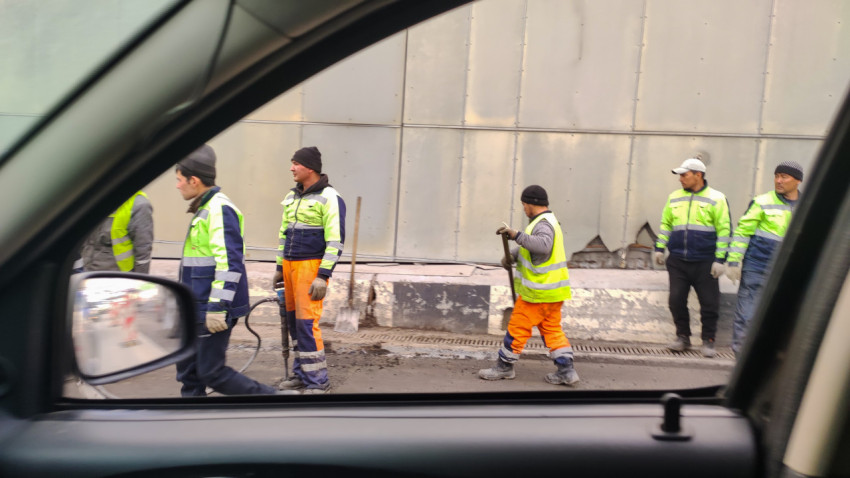 Дорожные рабочие выполняют ремонт у проезжей части