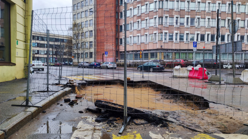 Провал асфальта у административного здания, ограждённый временным забором