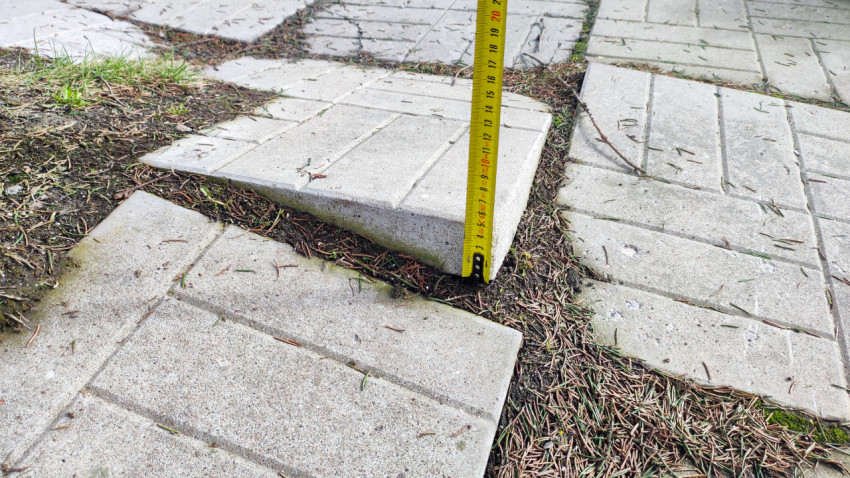 Измерение перепада высоты тротуарной плитки вертикальной рулеткой