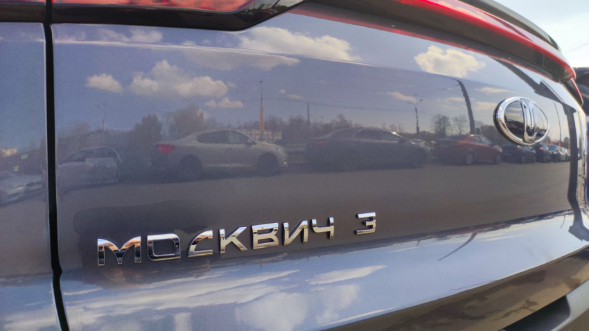 Задняя часть автомобиля Москвич 3 с логотипом и отражением города