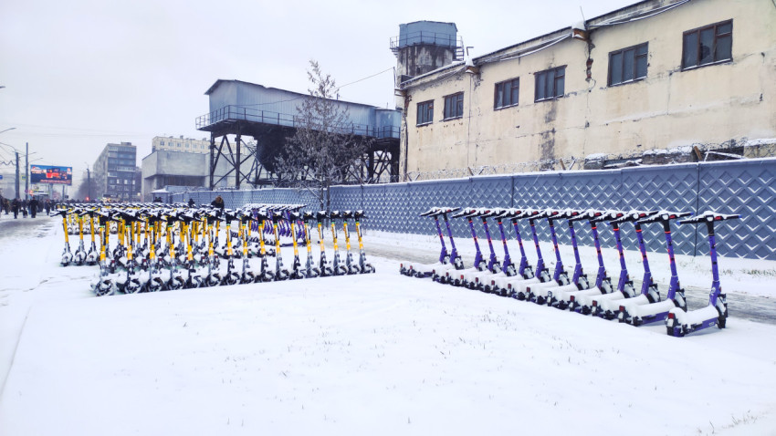 Электросамокаты на зимней площадке у промышленного здания