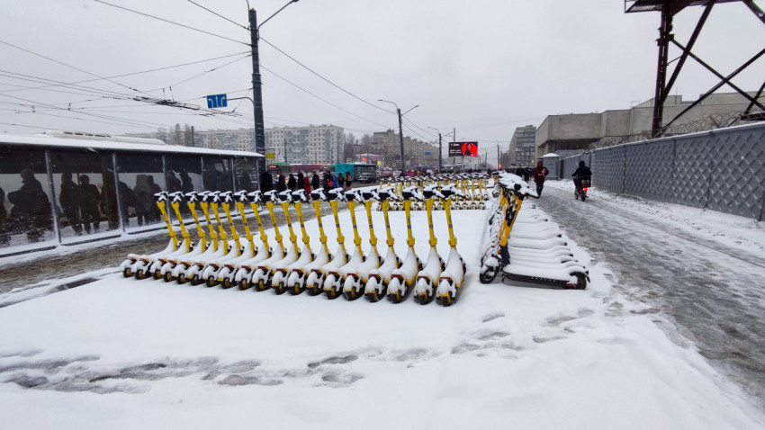 Зимняя парковка электросамокатов вдоль оживленной городской улицы