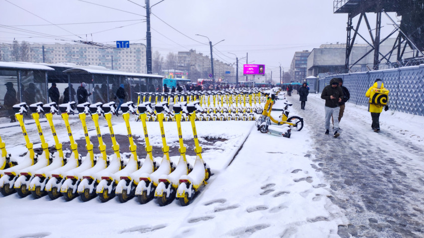 Зимняя стоянка электросамокатов у городского пешеходного потока