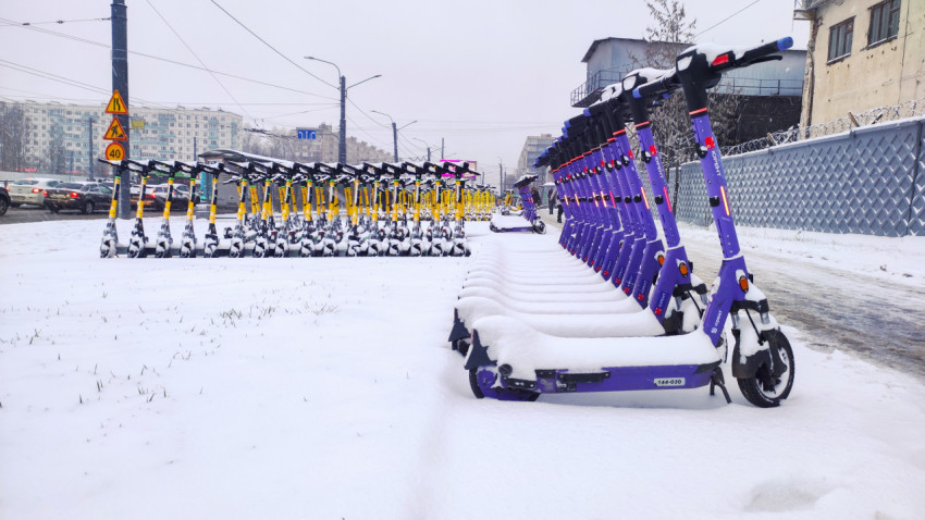 Ряды электросамокатов Юрент и Whoosh, покрытые снегом на городской улице