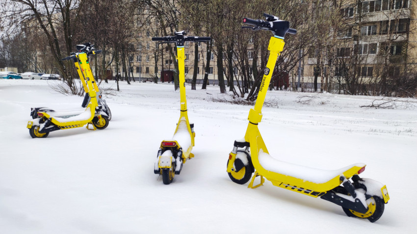 Электросамокаты в снегу на дворовой территории жилого района