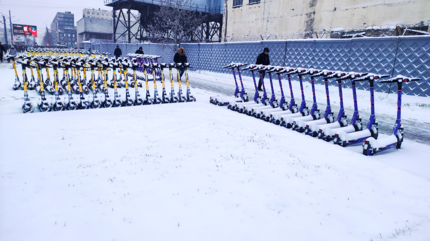 Колонна электросамокатов под снегом на открытой площадке