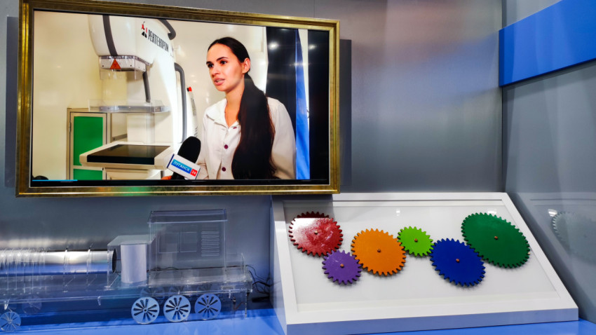 Экран с интервью и макетом шестерён на стенде ЛНР