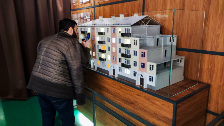 Посетитель фотографирует архитектурный макет жилого дома в павильоне «АТОМ» ВДНХ