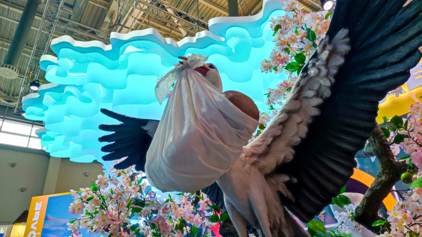 Декоративная композиция аиста с младенцем под световой инсталляцией на стенде Ставрополья
