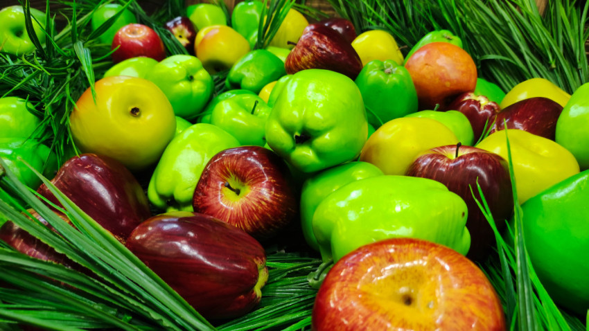 Смешанная выкладка зелёных и красных яблок среди декоративной травы