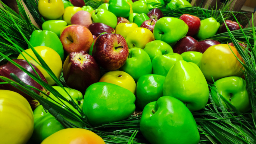 Яркая выкладка декоративных яблок в густой искусственной зелени