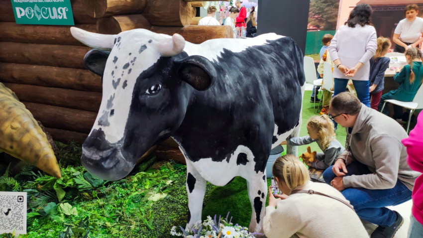Макет коровы среди посетителей на стенде Кировской области
