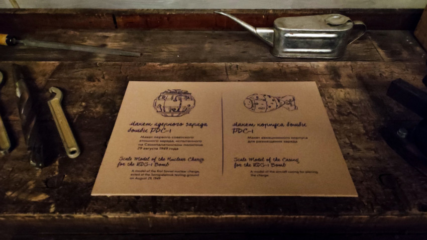 Табличка о макетах РДС-1 среди инструментов на деревянном верстаке