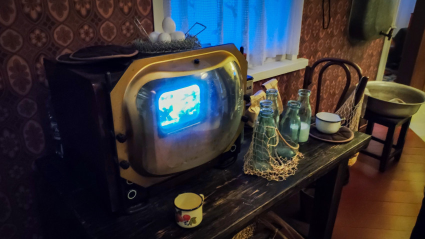 Ретро-телевизор с бутылочной тарой и предметами быта на столе