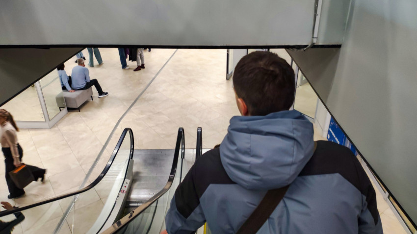 Посетитель спускается по эскалатору в здании выставки