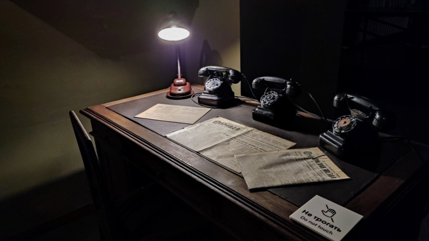 Ретро-телефоны и архивные газеты на письменном столе экспозиции